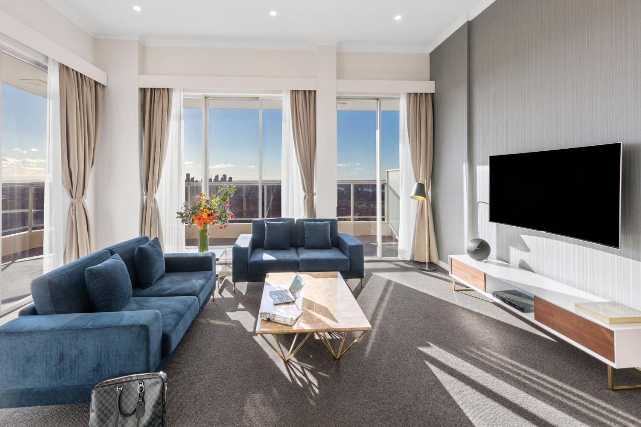 Meriton Suites Bondi Junction Sidney Dış mekan fotoğraf The photo depicts a modern living room with a stylish and contemporary design. It features a cozy seating arrangement with a blue sofa and two matching armchairs. In front of the seating area is a coffee table with a geometric design. The room has la