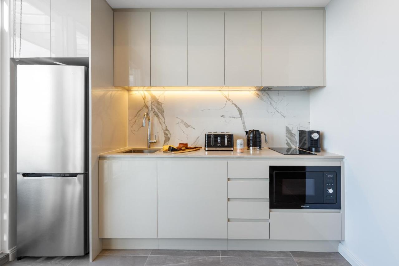 Meriton Suites Bondi Junction Sidney Dış mekan fotoğraf The photo shows a modern kitchen featuring a sleek design. It includes light-colored cabinetry with a smooth finish and upper cabinets that blend seamlessly with the wall. The countertop is made of a light stone, complementing the overall aesthetic. 